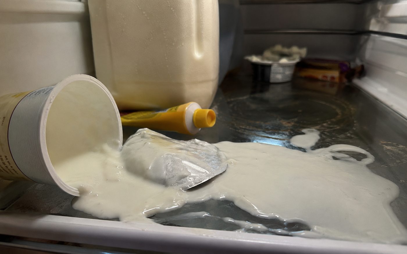 Umgekippter, ausgelaufener Joghurt auf der Glasablage im Kühlschrank